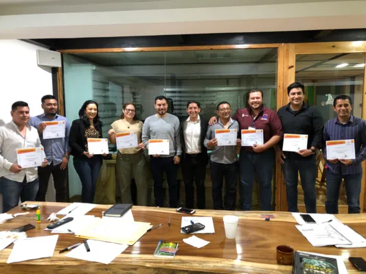 Trabajadores certificados mostrando diploma final después del curso especializado de ComprasMX. Grupo de trabajadores mostrando orgullosamente su diploma tras completar el curso ComprasMX de manera exitosa.